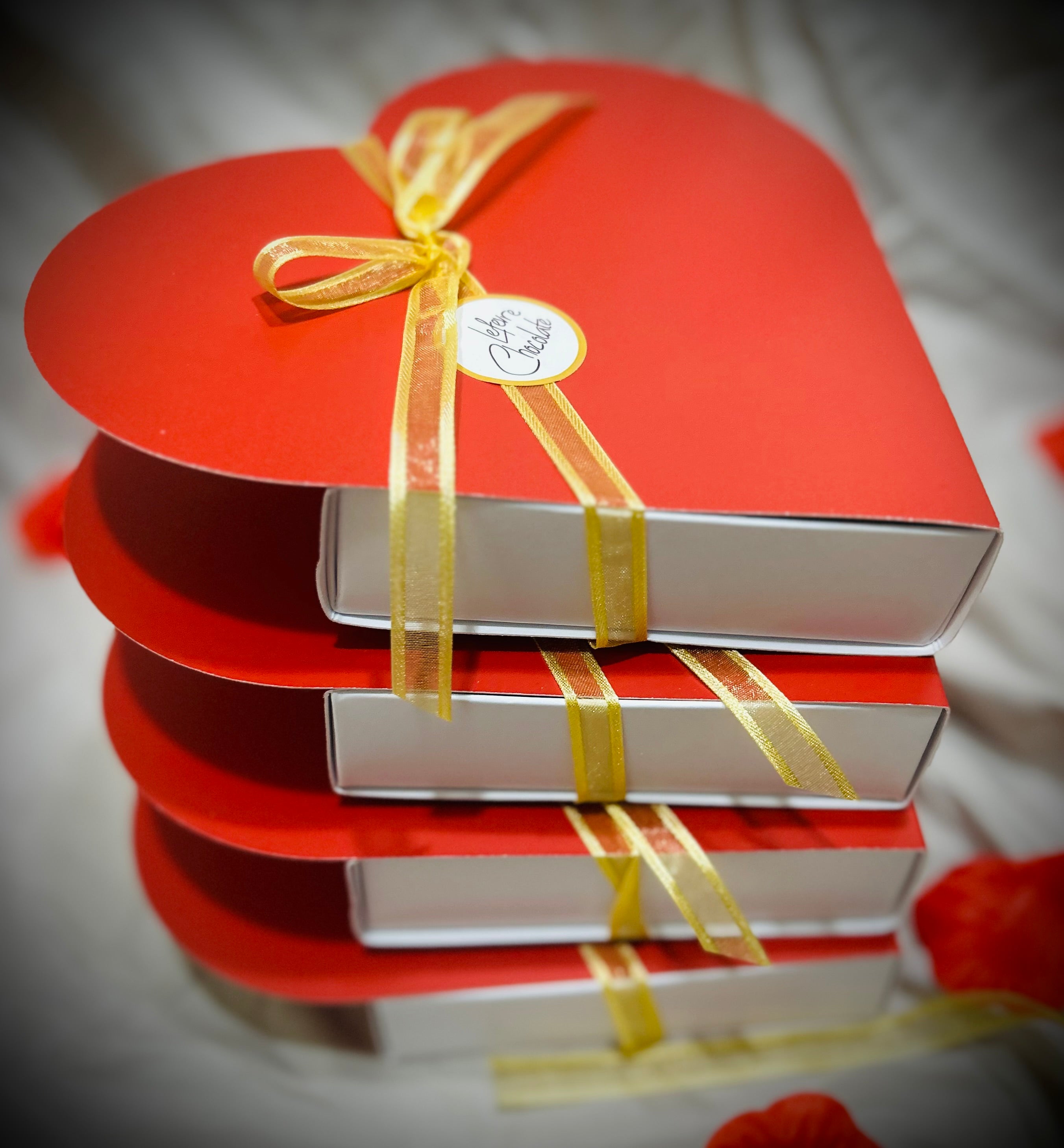 stack of chocolate boxes showing the Red heart-shaped gift box of 9 Lefevre Chocolate artisan Belgian chocolate truffles for Valentine's Day
